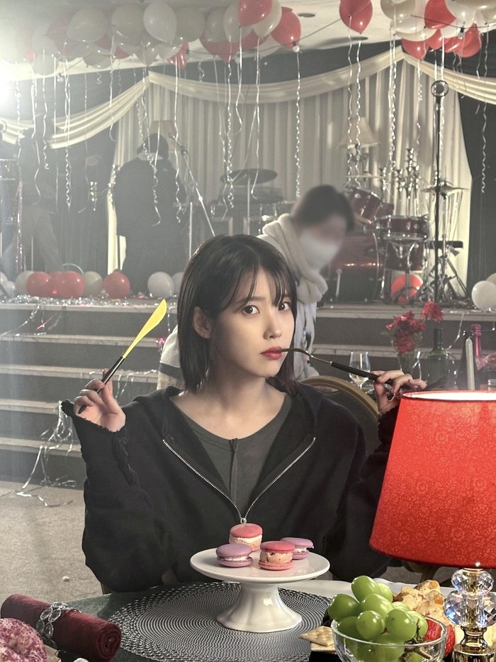 Foto belakang layar MV IU Love Wins All yang diperankan IU dan V BTS. MV ini disutradarai Um Tae Hwa dari film Concrete Utopia.