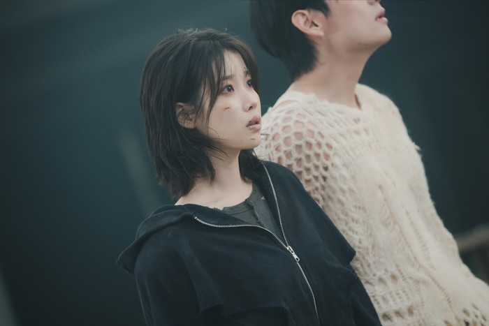 Foto belakang layar MV IU Love Wins All yang diperankan IU dan V BTS. MV ini disutradarai Um Tae Hwa dari film Concrete Utopia.