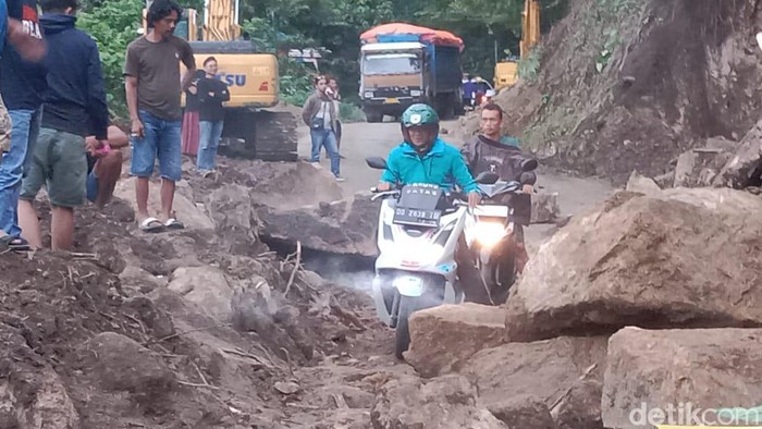 Pengendara sepeda motor berusaha melewati sela-sela material longsor di Tompo Ladang, Kabupaten Maros, Sulsel.