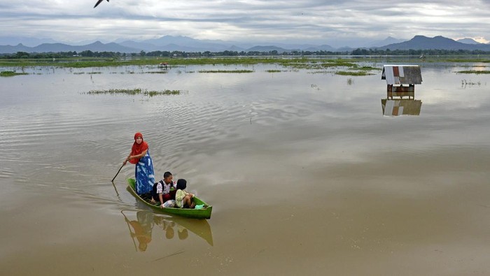 Warga menggunakan sampan untuk menyeberangi rawa dari Desa Kajenjeng menuju ke Kampung Romang Tangayya, Makassar, Sulawesi Selatan, Kamis (25/1/2024). Sejumlah warga dan anak sekolah terpaksa menggunakan sampan untuk menyeberangi area persawahan yang terendam banjir akibat intensitas hujan lebat di Kota Makassar dalam beberapa hari ini. ANTARA FOTO/Hasrul Said/YU/foc.