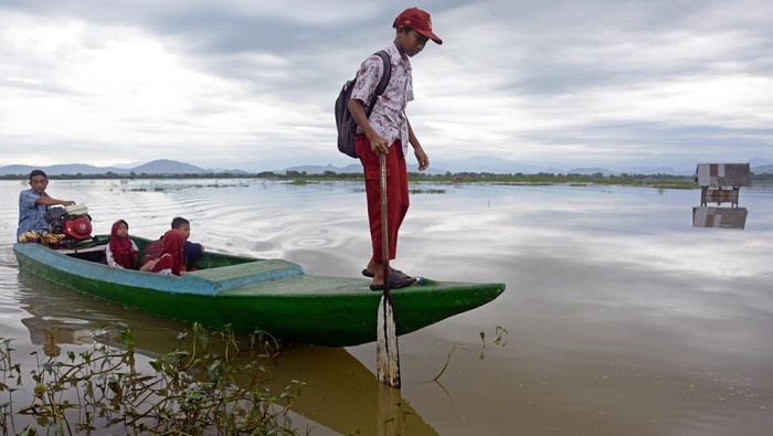 Warga menggunakan sampan untuk menyeberangi rawa dari Desa Kajenjeng menuju ke Kampung Romang Tangayya, Makassar, Sulawesi Selatan, Kamis (25/1/2024). Sejumlah warga dan anak sekolah terpaksa menggunakan sampan untuk menyeberangi area persawahan yang terendam banjir akibat intensitas hujan lebat di Kota Makassar dalam beberapa hari ini. ANTARA FOTO/Hasrul Said/YU/foc.