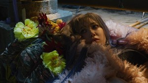 Kemudian Sakura muncul tengah tertidur dalam kehangatan coat berbulu pink yang kemudian digunakannya berjalan menuju dinding batu. Kejutan muncul di akhir adegan tersebut. (Foto: dok. Source Music)