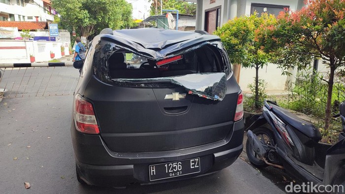 Satu buah mobil ringsek usai tertimpa pohon di depan SMK Grafika, Semarang, Jumat (26/1/2024).