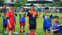 Tak berselang lama, Jokowi keluar dengan mengenakan baju timnas Indonesia berwarna merah dan bertopi hitam. Ia kemudian berjalan menuju lapangan dengan menggunakan payung.