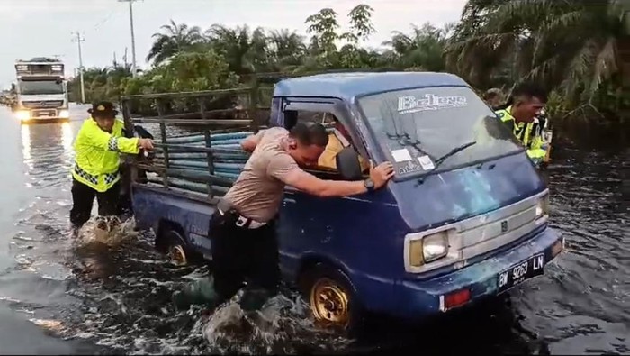 Polisi saat membantu pengendara mogok akibat jalan terendam banjir