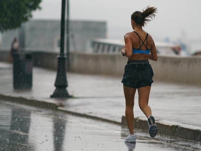 Moscow, Russia, June 27, 2021: Rainy day in city at summer. Wet jogger has sport activity. Texture of strong, fresh and powerful water drops and sprays. Back, rear view