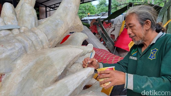 Seorang pekerja sedang Dinas Lingkungan Hidup (DLH) Pemkot Surabaya sedang menyelesaikan pembuatan Lion Naga 3D untuk menyambut Imlek, Minggu (28/1/2024).