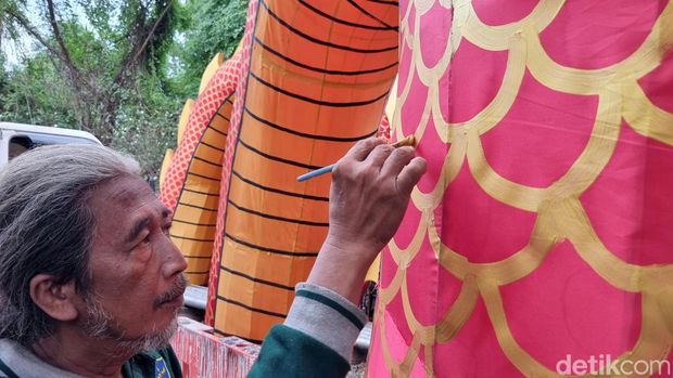 Seorang pekerja sedang Dinas Lingkungan Hidup (DLH) Pemkot Surabaya sedang menyelesaikan pembuatan Lion Naga 3D untuk menyambut Imlek, Minggu (28/1/2024).