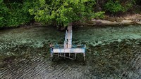 Pengunjung berfoto di jembatan Pantai Air Panas di Desa Tawa, Pulau Bacan, Halmahera Selatan, Maluku Utara, Minggu (28/1/2024).
