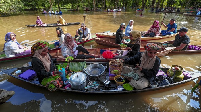 Pedagang dan pengunjung mendayung perahu tradisional saat dibukanya Pasar Apung di kawasan Situs Candi Astano yang terendam banjir yaitu Kawasan Cagar Budaya Nasional (KCBN) Muara Jambi, Muaro Jambi, Jambi, Minggu (28/1/2024). Pasar Apung yang dikelola oleh komunitas budaya bersama Balai Pelestarian Kebudayaan (BPK) Wilayah V tersebut menyediakan jajanan lokal dari pelaku UMKM setempat yang dibuka beberapa hari setelah kawasan itu terendam banjir luapan Sungai Batanghari. ANTARA FOTO/Wahdi Septiawan/nym.