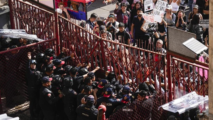 Police block a gate as animal rights activists try to enter the Plaza Mexico, in Mexico City, Sunday, Jan. 28, 2024. Bullfighting returned to Mexico City after the Supreme Court of Justice overturned a 2022 ban that prevented these events from taking place in the capital. (AP Photo/Fernando Llano)