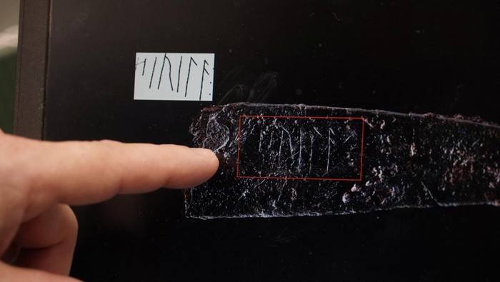 Jakob Bonde, curator and archaeologist at Museum Odense, points at a photograph of a blade with a runic inscription that he has dated to be around 2,000 years old, in the museum at Odense, Denmark, January 26, 2024. REUTERS/ Tom Little