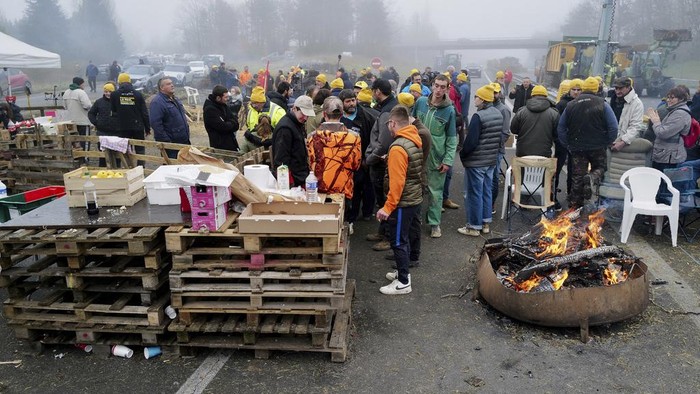 Gedung Pemerintah Prancis Dipenuhi Sampah Imbas Protes Petani People watch slurry, manure and tyres dumped by farmers at the entrance of the local state administration building, in Agen, southwestern France, Saturday, Jan. 27, 2024. French farmers have vowed to continue protesting and are maintaining traffic barricades on some of the country's major roads. The government announced a series of measures Friday but the farmers say these do not fully address their demands. (AP Photo/Fred Scheiber)