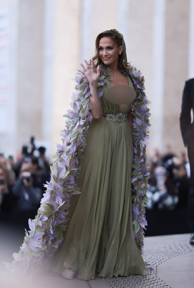 Berpose untuk para juru foto, Jennifer Lopez terlihat glamour dengan cape bunga yang panjangnya menyapu lantai. Foto: Jeremy Moeller/Getty Images