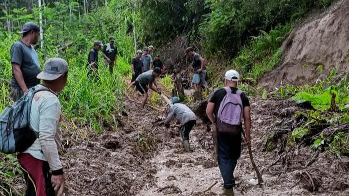 Warga saat gotong royong perbaiki jalan usai ditimbun tanah longsor di Merangin Jambi.