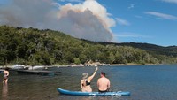 Sejumlah turis dengan santai berenang di Danau Futalaufquen saat hutan di Taman Nasional Los Alerces terbakar.