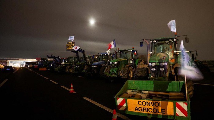 People gather during a blockade by farmers on the A4 highway to protest over price pressures, taxes and green regulation, grievances that are shared by farmers across Europe, in Jossigny, near Paris, France, January 30, 2024. REUTERS/Yves Herman
