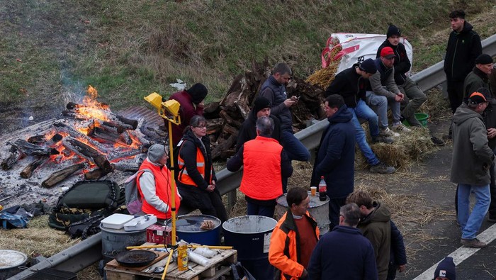 People gather during a blockade by farmers on the A4 highway to protest over price pressures, taxes and green regulation, grievances that are shared by farmers across Europe, in Jossigny, near Paris, France, January 30, 2024. REUTERS/Yves Herman