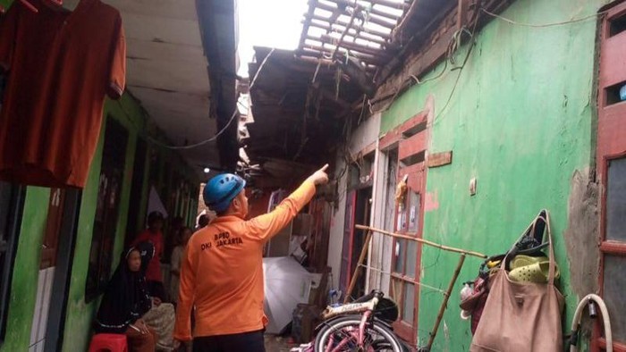 Seorang petugas BPBD DKI Jakarta sedang meninjau rumah roboh di Semanan, Kalideres, Jakarta Barat, Selasa (30/1/2024)
