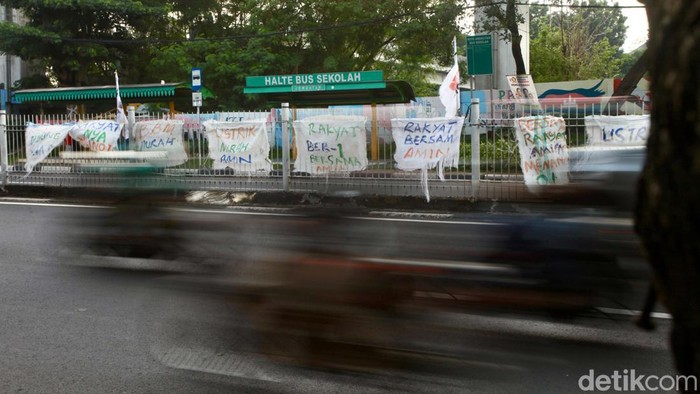 Spanduk dukungan terhadap Anies-Muhaiman berjejer di jalan Taman Mini, Jaktim. Spanduk tersebut tersebut dari karung dan ditulis tangan.