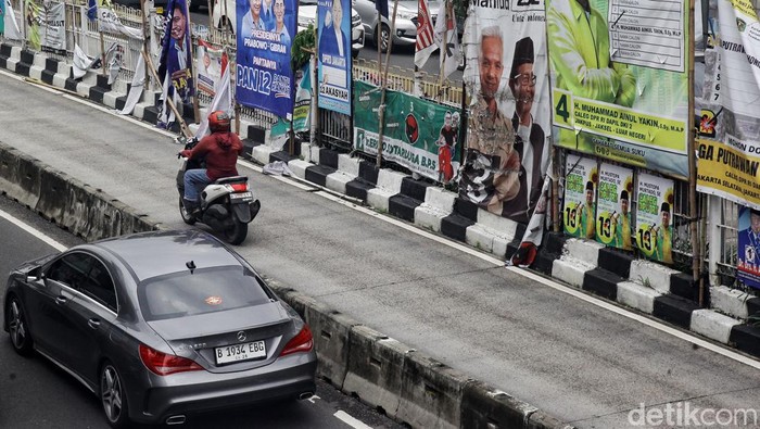 Pengendara melintas di antara deretan alat peraga kampanye berupa bendera partai politik, spanduk calon legislatif dan capres-cawapres di Mampang Prapatan, Jakarta Selatan, Rabu (31/1/2024). Tak sedikit APK yang berada di median jalan dan JPO tersebut lusuh, kotor maupun robek lantaran faktor cuaca dan sudah lama terpasang. Akibatnya, APK membuat kumuh dan merusak keindahan kota.