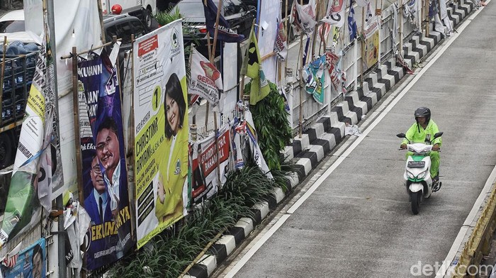 APK Lusuh dan Kotor di Median Jalan Pengendara melintas di antara deretan alat peraga kampanye berupa bendera partai politik, spanduk calon legislatif dan capres-cawapres di Mampang Prapatan, Jakarta Selatan, Rabu (31/1/2024). Tak sedikit APK yang berada di median jalan dan JPO tersebut lusuh, kotor maupun robek lantaran faktor cuaca dan sudah lama terpasang. Akibatnya, APK membuat kumuh dan merusak keindahan kota.