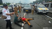 Mereka memanjat tembok pembatas jalan tol di sisi Jalan Gatot Subroto.  