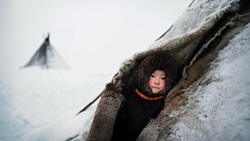 Karya Tommaso Vecchi. “Nenets adalah masyarakat adat Siberia yang perekonomian tradisionalnya telah lama berakar pada penggembalaan rusa kutub, penangkapan ikan, dan perburuan. Mereka tinggal di chums: gubuk kecil yang terbuat dari kulit rusa, untuk memastikan isolasi termal minimal, terutama selama musim dingin. Dalam gambar ini Roman melihat ke luar dari sahabatnya, dengan pipinya yang merah karena suhu dingin, -50°C.” Foto: International Photography Awards