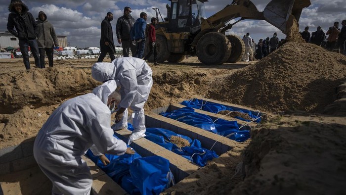 Israel Kembalikan 100 Jenazah Warga Gaza, Langsung Dimakam Massal Palestinians bury the bodies of people who were killed in fighting with Israel and returned to Gaza by the Israeli military, during a mass funeral in Rafah, Gaza Strip, Tuesday, Jan. 30, 2024. (AP Photo/Fatima Shbair)