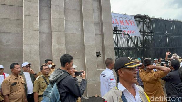Massa demo Apdesi merusak tembok pagar DPR dengan palu besar.