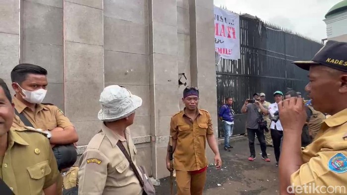Massa demo Apdesi merusak tembok pagar DPR dengan palu besar.
