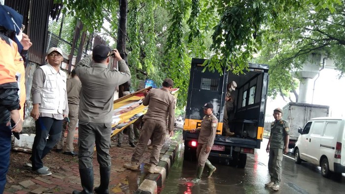 Petugas gabungan menertibkan APK yang melanggar aturan di Jakarta Barat