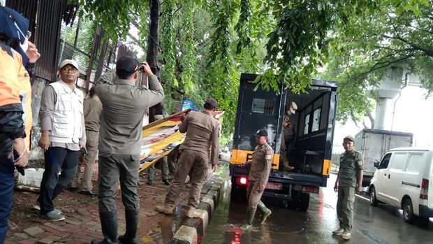 Petugas gabungan menertibkan APK yang melanggar aturan di Jakarta Barat