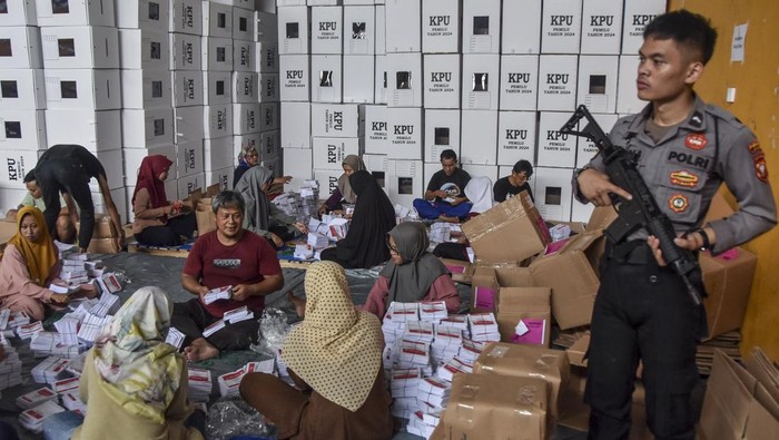 Polisi bersenjata berjaga di samping pekerja saat mengemas logistik Pemilu di Gudang Logistik, Imbanagara, Ciamis, Jawa Barat, Rabu (31/1/2023). KPU Ciamis melakukan pengaturan dan pengemasan logistik Pemilu 2024 untuk didistribusikan secara bertahap di 3.943 TPS pada 1-13 Pebruari 2024. ANTARA FOTO/Adeng Bustomi/nym.