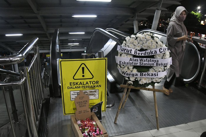 Seorang penumpang kereta melakukan aksi dengan membawa bunga bertuliskan ?Turut berduka cita atas wafatnya satu eskalator? di Stasiun Bekasi, Jawa Barat, Rabu (31/1/2024). Aksi tersebut sebagai bentuk kritik penumpang angkutan umum kereta karena sudah 100 hari, satu eskalator di stasiun rusak sehingga menganggu kenyamanan penumpang.