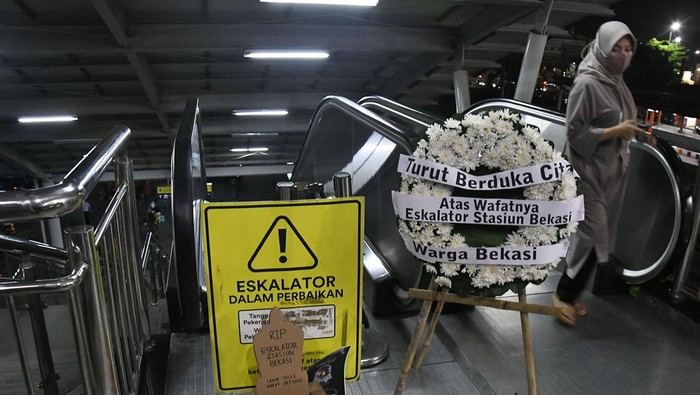 Seorang penumpang kereta melakukan aksi dengan membawa bunga bertuliskan ?Turut berduka cita atas wafatnya satu eskalator? di Stasiun Bekasi, Jawa Barat, Rabu (31/1/2024). Aksi tersebut sebagai bentuk kritik penumpang angkutan umum kereta karena sudah 100 hari, satu eskalator di stasiun rusak sehingga menganggu kenyamanan penumpang.