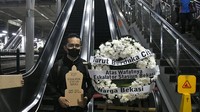 Seorang penumpang KRL melakukan aksi dengan membawa karangan bunga bertuliskan Turut Berduka Cita Atas Wafatnya Eskalator di Stasiun Bekasi, Rabu (31/1/2024).