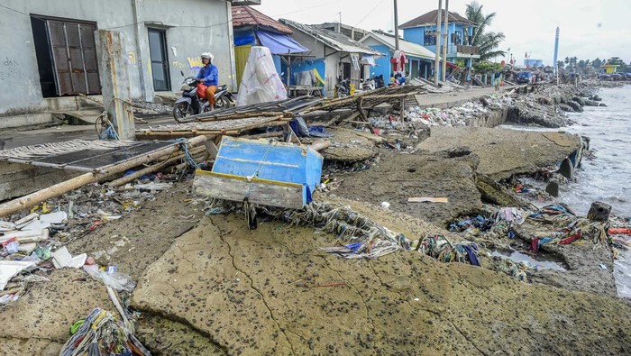 Dampak gelombang tinggi di Pandeglang Pengendara roda dua melintas di samping dermaga yang rusak akibat gelombang tinggi di Teluk Labuan, Pandeglang, Banten, Kamis (1/2/2024). Gelombang tinggi yang terjadi sejak sepekan terakhir tersebut mengakibatkan dermaga tempat berlabuh kapal nelayan menjadi rusak serta jalan yang berada di sekitar area dermaga ambles. ANTARA FOTO/Muhammad Bagus Khoirunas/foc.