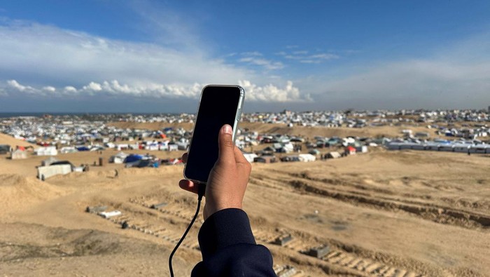 Displaced Palestinians try to get internet signal to communicate with their relatives, amid the ongoing conflict between Israel and Hamas, at the border with Egypt, in Rafah in the southern Gaza Strip February 1, 2024. REUTERS/Mohammed Salem