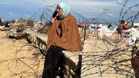 Seorang pengungsi Palestina berkomunikasi dengan kerabatnya di perbatasan Mesir. 