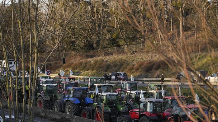 Jaringan Petani di Eropa Blokir Ratusan Jalan dengan Traktor Farmers watch their tractors from a bridge on a blocked highway, Wednesday, Jan. 31, 2024 in Chilly-Mazarin, south of Paris. French farmers maintained their protests on major roads around Paris and across the country on Wednesday as police was deployed to protect the capital, its airports and an international market. (AP Photo/Christophe Ena)