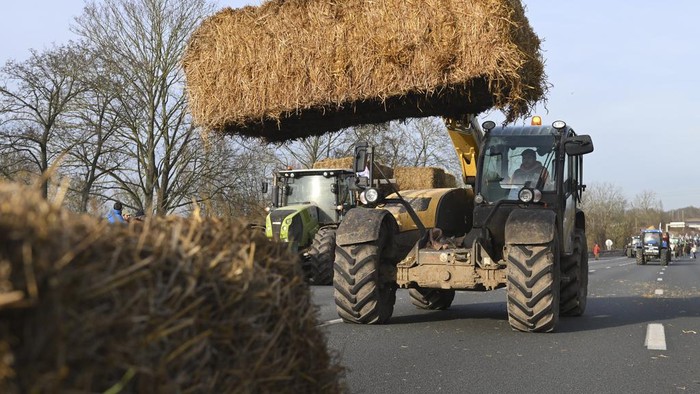 Farmers install hay bales on a highway near Paris's main airport, Monday, Jan. 29, 2024 near Roissy-en-France, north of Paris. Protesting farmers were encircling Paris with tractor barricades and drive-slows on Monday, using their lumbering vehicles to block highways leading to France's capital to pressure the government over the future of their industry, which has been shaken by repercussions of the Ukraine war. (AP Photo/Matthieu Mirville)