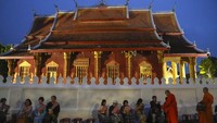 Orang-orang menawarkan makanan kepada biksu Buddha di luar kuil Sensoukharam di Luang Prabang, Laos, Minggu (28/1/2024).