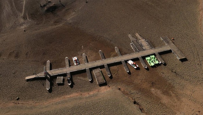 Residents look at pedal boats sitting on a cracked ground at a Sau reservoir, as the Iberian peninsula is at its driest in 1,200 years, in Sant Roma De Sau, Spain, January 31, 2024. REUTERS/Nacho Doce
