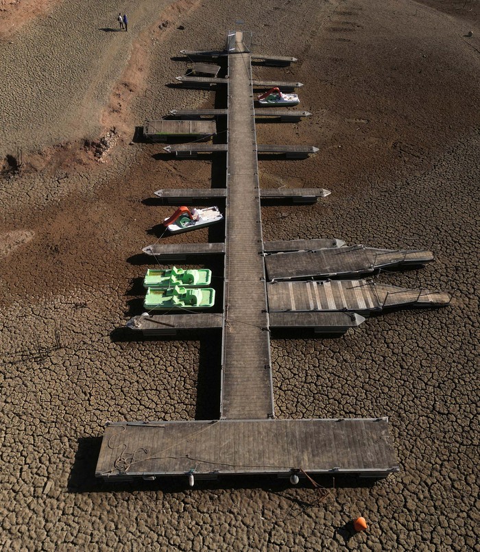 Residents look at pedal boats sitting on a cracked ground at a Sau reservoir, as the Iberian peninsula is at its driest in 1,200 years, in Sant Roma De Sau, Spain, January 31, 2024. REUTERS/Nacho Doce