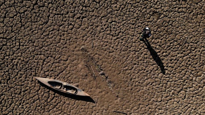 Residents look at pedal boats sitting on a cracked ground at a Sau reservoir, as the Iberian peninsula is at its driest in 1,200 years, in Sant Roma De Sau, Spain, January 31, 2024. REUTERS/Nacho Doce