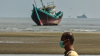 Warga melintas di depan kapal pengangkut imigran etnis Rohingya yang terdampar di Pantai Kuala Parek, Kecamatan Sungai Raya, Kabupaten Aceh Timur, Aceh, Kamis (1/2/2024). (ANTARA FOTO/Humaira)  