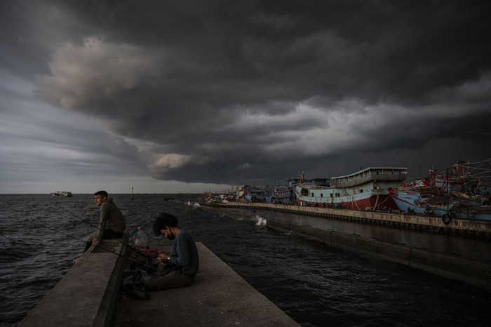 Warga memancing dengan latar belakang awan mendung di kawasan Pelabuhan Nizam Zachman, Muara Baru, Jakarta, Jumat (2/2/2024). Badan Penanggulangan Bencana Daerah (BPBD) DKI Jakarta mengimbau masyarakat Jakarta untuk mewaspadai dan mengantisipasi dampak dari cuaca ekstrem pada awal Februari 2024. ANTARA FOTO/Aprillio Akbar/YU
