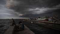 Warga memancing dengan latar belakang awan mendung di kawasan Pelabuhan Nizam Zachman, Muara Baru, Jakarta, Jumat (2/2/2024).