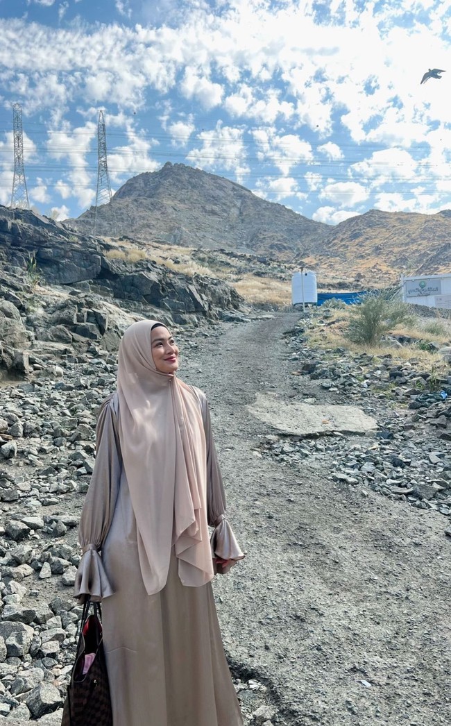 Titi Kamal memakai hijab pashmina warna nude yang dipadu dengan dres shimmer silk warna senada saat berpose di kawasan Jabal Tsur, Mekkah.  Foto: Dok. Instagram @titi_kamall.